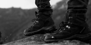 Close-up of hiking boots standing on a rock, showcasing outdoor adventure style in monochrome.