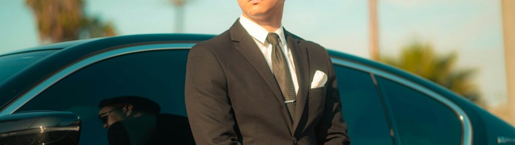 man in black suit standing beside black car during daytime