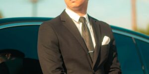 man in black suit standing beside black car during daytime