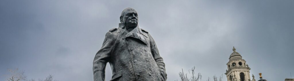 A statue of a man holding a cane in front of a building