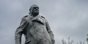 A statue of a man holding a cane in front of a building