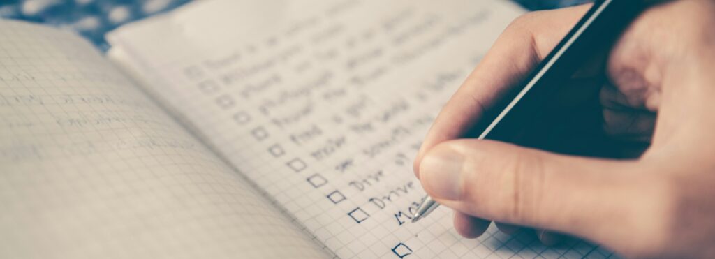 person writing bucket list on book