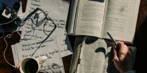 man in black long sleeve shirt writing on white paper