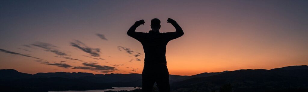 a man standing on top of a bench at sunset
